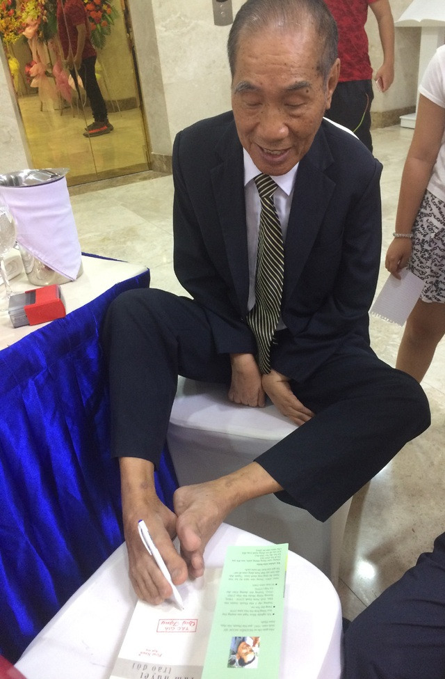 Thầy Nguyễn Ngọc Ký dùng đôi chân của mình ký tặng sách cho bạn đọc.